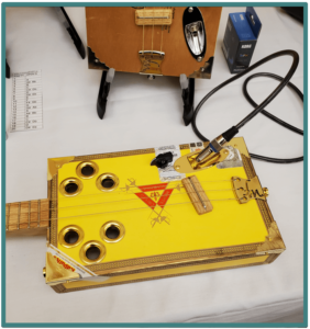 Edmonton Guitar Show- Image of an a cigar box guitar body with resonator holes 