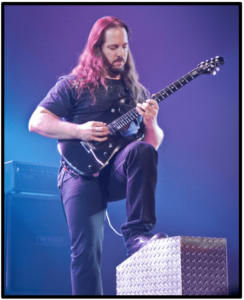 prevent hand pain-image of John Petrucci playing live with his guitar in a classical postion and left leg lifted