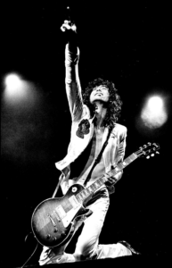 prevent hand pain-image of Jimmy Page playing live in black and white with his guitar strung very low