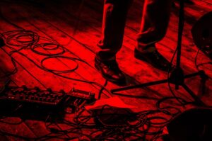 How To Get Back Onstage- An image of a guitarist feet on a red stage with his peddles all over his area