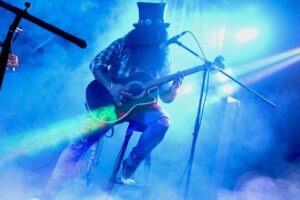 guitar popular- an image of Slash playing live on a stool with an ovation 